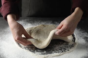 Woman kneading pizza dough at table, closeup