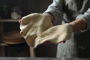Woman tossing pizza dough in kitchen, closeup