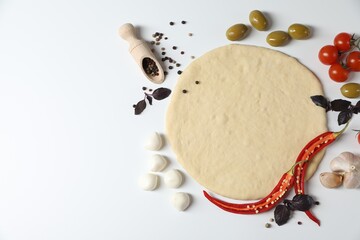 Fresh pizza dough and products on white background, flat lay. Space for text