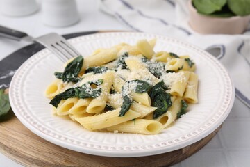 Tasty pasta with spinach and cheese on white tiled table, closeup