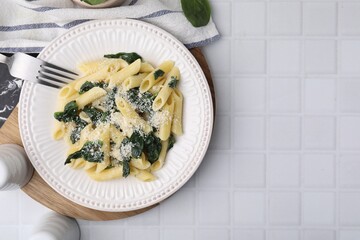 Tasty pasta with spinach and cheese served on white tiled table, flat lay. Space for text