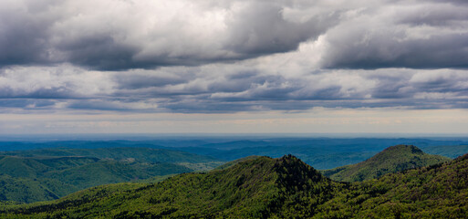 Obraz premium Rolling green hills and valleys under a cloudy sky