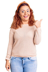 Obraz premium Young latin woman wearing casual clothes and diadem smiling with happy face looking and pointing to the side with thumb up.