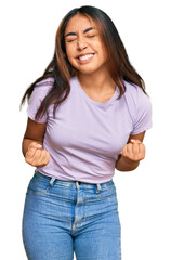 Fototapeta premium Young latin woman wearing casual clothes very happy and excited doing winner gesture with arms raised, smiling and screaming for success. celebration concept.