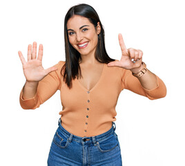 Young hispanic woman wearing casual clothes showing and pointing up with fingers number seven while smiling confident and happy.