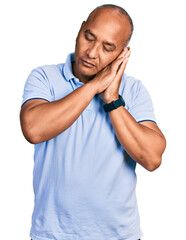 Hispanic middle age man wearing casual t shirt sleeping tired dreaming and posing with hands together while smiling with closed eyes.