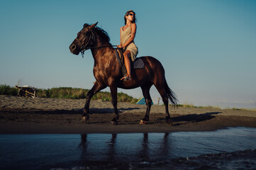 Attractive girl galloping on a horse on an ocean coast