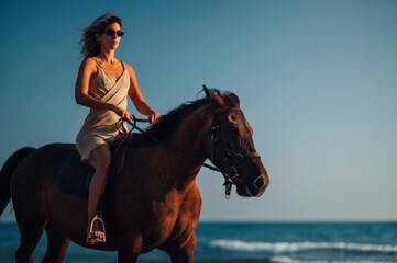 Low angle portrait of a female rider riding her horse at the seacoast