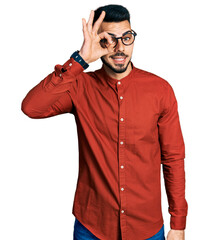 Young hispanic man with beard wearing business shirt and glasses doing ok gesture with hand smiling, eye looking through fingers with happy face.
