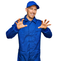 Bald man with beard wearing builder jumpsuit uniform smiling funny doing claw gesture as cat, aggressive and sexy expression
