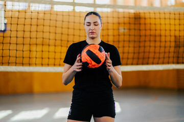 Girl preparing to serve a ball while playing volleyball in a sports hall