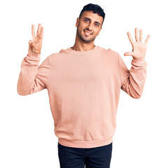 Young hispanic man wearing casual clothes showing and pointing up with fingers number eight while smiling confident and happy.