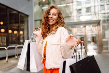 Cheerful woman holding shopping bags. Beautiful woman in casual style shopping in the city....