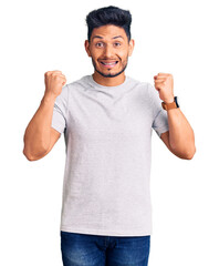 Fototapeta premium Handsome latin american young man wearing casual tshirt celebrating surprised and amazed for success with arms raised and open eyes. winner concept.