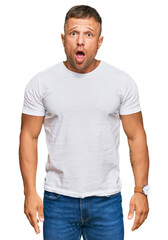 Obraz premium Handsome muscle man wearing casual white tshirt afraid and shocked with surprise and amazed expression, fear and excited face.