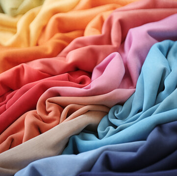 Pila de camisetas dobladas de colores.Primer plano de una prenda de moda con los colores del arco iris. Fondo de diferentes prendas de colores, muestrario de telas abstracto.