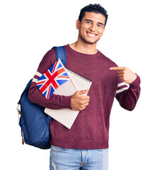 Hispanic handsome young man exchange student holding uk flag pointing finger to one self smiling...