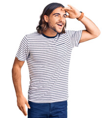 Young handsome man wearing casual clothes very happy and smiling looking far away with hand over head. searching concept.