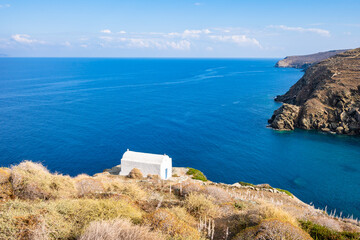 View of small chapel overlooking sea bay and rocky coast cliffs from Kastro village, Sifnos island,...