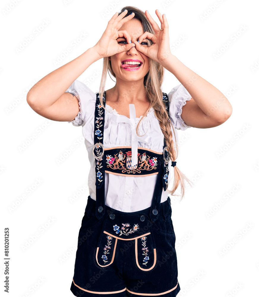 Sticker Young beautiful blonde woman wearing oktoberfest dress doing ok gesture like binoculars sticking tongue out, eyes looking through fingers. crazy expression.