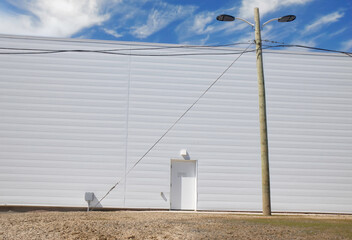 Exterior elevation of a wall on a large industrial building, horizontal beige siding, single white...