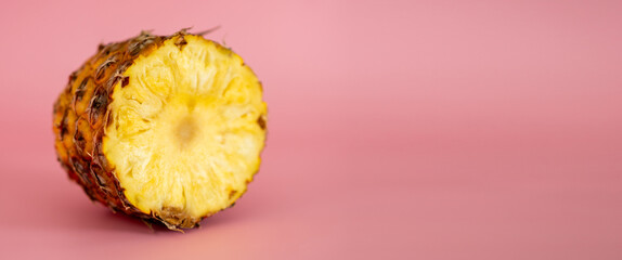 A slice of pineapple is shown on a pink background