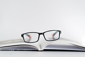 A pair of glasses is on top of an open book
