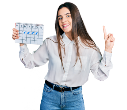 Young brunette teenager holding travel calendar smiling with an idea or question pointing finger with happy face, number one