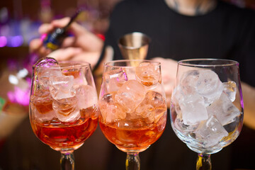 Bartender pours pink cocktail into martini glass with flair