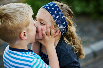 Kids, siblings and kiss with love in outdoor for bonding, family and holiday, travel and youth in...
