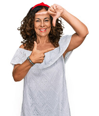 Middle age hispanic woman wearing casual clothes smiling making frame with hands and fingers with happy face. creativity and photography concept.