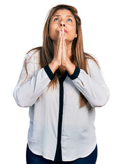 Middle age latin woman wearing business shirt begging and praying with hands together with hope expression on face very emotional and worried. begging.