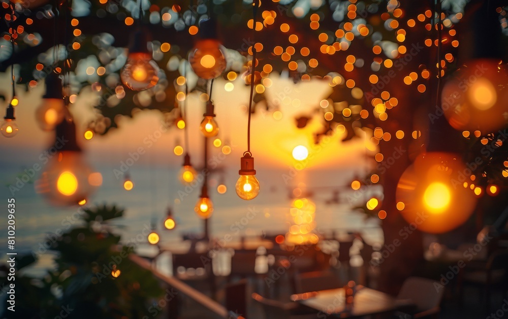 Poster a tree with lights hanging from it and a sunset in the background