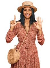 Young african american woman wearing summer hat showing and pointing up with fingers number seven...