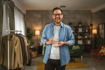 Portrait of adult caucasian man sit and hold glass of water at home