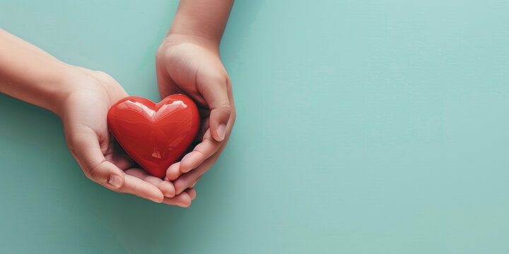 Woman hands holding red heart on solid light blue background. Health care, organ donation, cardiac health problems.