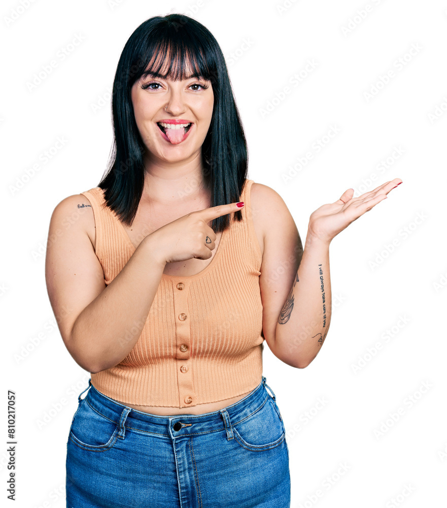 Sticker young hispanic plus size woman pointing open palm with finger sticking tongue out happy with funny e