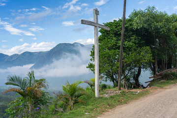 Wooden cross on the edge of a rural road with mountains landscape in the background in Colombia