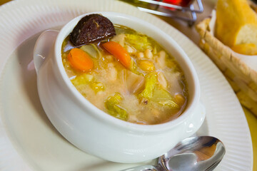 Catalan soup cooked with bean, carrots and potatoes served with black sausage in bowl