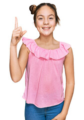 Beautiful brunette little girl wearing summer pink shirt pointing finger up with successful idea. exited and happy. number one.