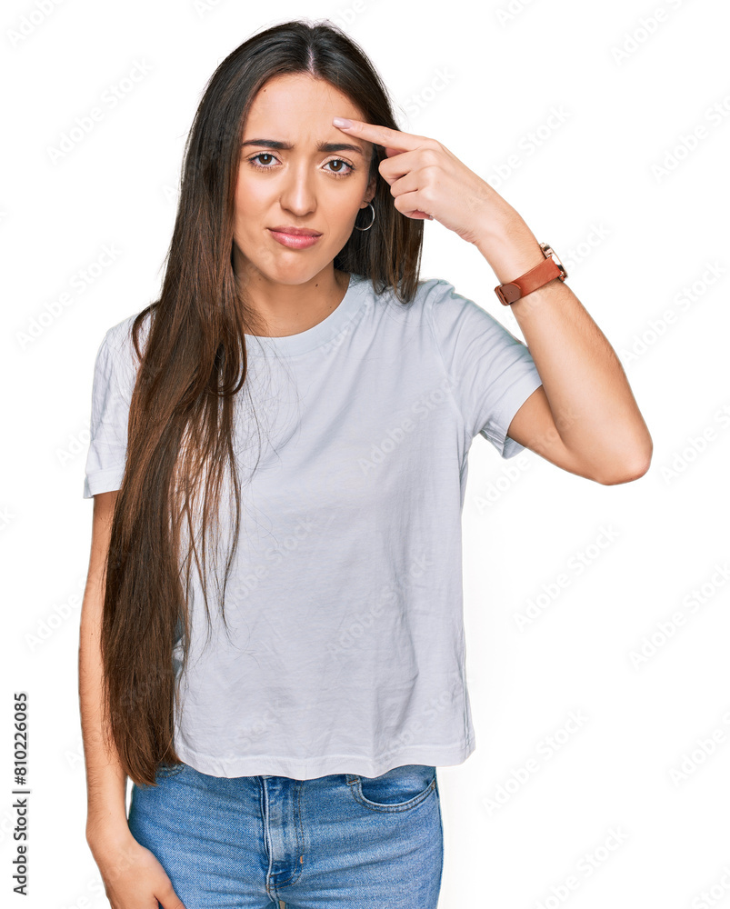 Poster young hispanic girl wearing casual white t shirt pointing unhappy to pimple on forehead, ugly infect