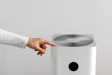 Cropped shot of woman hand pressing button on household air purifier