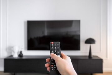 Woman hand hold remote control, press button and turn on television