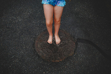 feet splashing in a puddle over a manhole cover