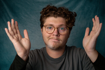 Man with Glasses Shrugging Portrait with Blue Background.