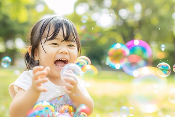 A child laughing joyously while blowing colorful bubbles in a sunny park, with the park scenery softly blurred