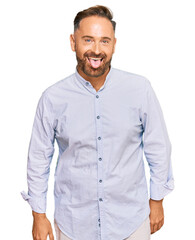 Handsome middle age man wearing business shirt sticking tongue out happy with funny expression. emotion concept.