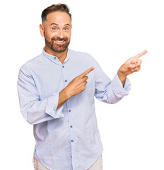Handsome middle age man wearing business shirt smiling and looking at the camera pointing with two hands and fingers to the side.