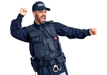 Fototapeta premium Young hispanic man wearing police uniform dancing happy and cheerful, smiling moving casual and confident listening to music