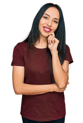 Young hispanic girl wearing casual t shirt looking confident at the camera with smile with crossed arms and hand raised on chin. thinking positive.